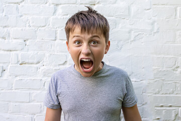 screaming Angry boy teenager with his mouth wide open and with open eyes against background of a...