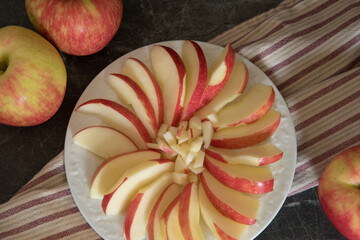 Nutritious sliced apple in a flower shape on a white plate for a healthy snack.