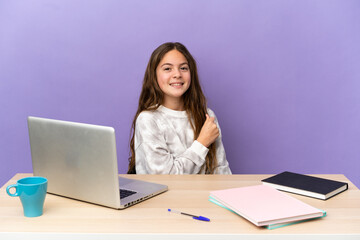 Little student girl in a workplace with a laptop isolated on purple background celebrating a victory