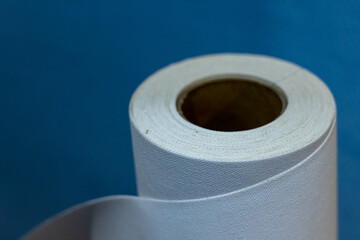Roll of cotton canvas on a blue background with bokeh. Close-up.