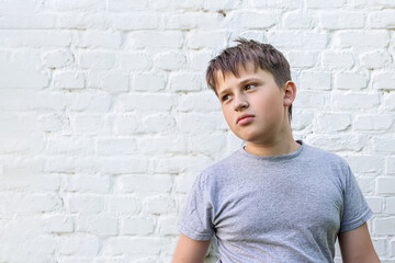 sad teenager looks away. child with empty look against background of a brick wall. Upset embarrassed woman feeling unhappy because of problems, quarrel