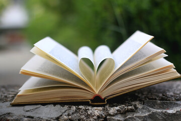 Vintage book with pages shaped like heart. Selective focus.