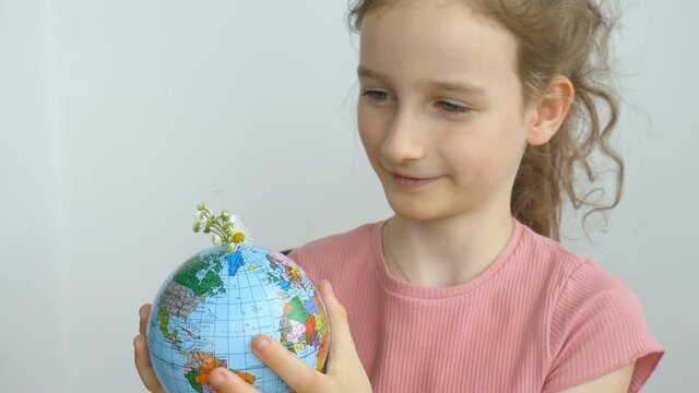 Earth globe with geographical names in Ukrainian cyrillic letters with flowers growing from it is held by a little blond girl. Human responsibility, world in hands, environmentally friendly concepts