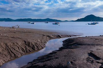 Beautiful reflections of tidal flats on the sea shore. Landscape of fishing boats floating in the sea. Ganghwado Island, Incheon, South Korea.