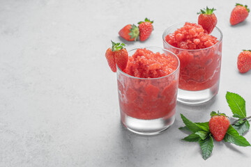Sicilian strawberry granita. Traditional Italian summer dessert in two glasses on light grey stone background with copy space. The perfect way to cool off. Horizontal orientation. Selective focus.