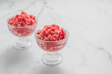 Sicilian strawberry granita. Traditional Italian summer dessert in two glasses on marble stone background with copy space. Berry ice cream. The perfect way to cool off. Horizontal orientation. 