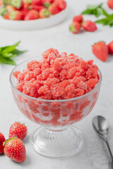 Sicilian strawberry granita traditional summer dessert in cup on light grey stone background the perfect way to cool off. Vertical orientation, close up. Selective focus.