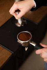 Fototapeta na wymiar Barista holding portafilter and coffee tamper making an espresso coffee.