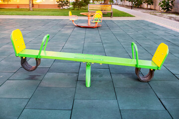 Empty seesaw on playground with soft rubber flooring in public park