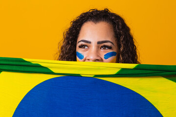 Misterious black woman fan holding a Brazilian flag in your face. Brazil colors in background,...