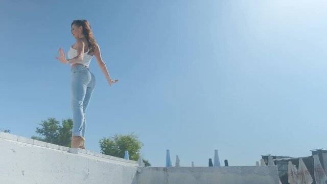 A girl in jeans is dancing bachata on the street on a summer sunny day.