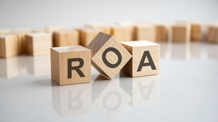 ROA - Return On Assets acronym concept on cubes, gray background