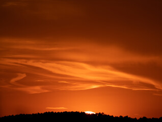 Orange sunset with clouds in flow and mountain range