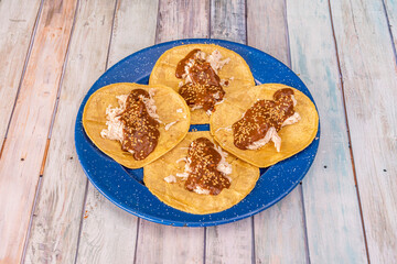 Tray of four Mexican chicken tacos with mole, sesame seeds and corn tortillas