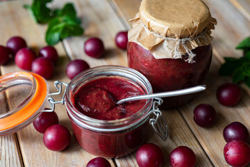 Preparation for the winter: spicy cherry plum ketchup in jars on a wooden table. Plum sauce....