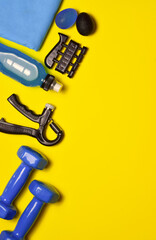 Hand grip fitness training and various accessories, on a yellow background. Copy space.