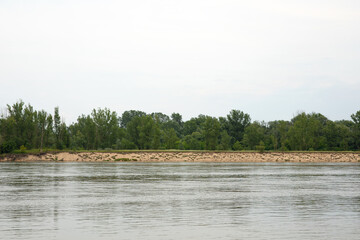 A calm river and green trees on a cloudy but beautiful day