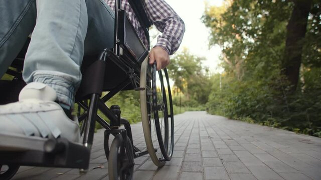 Moving wheelchair driven by disabled man, closeup. Concept of consequences of car accident and diagnosis paralysis