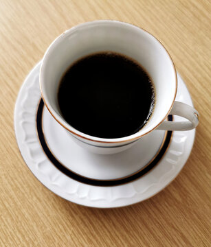 Top view image of a cup of black coffee on a wooden table