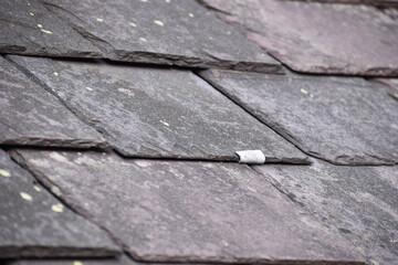 Close up of an old slate hook repair holding a Welsh slate tile in place.