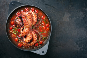 Traditional Italian polpo alla griglia in salsa di pomodoro with barbecued octopus in tomato sauce served as top view on a modern design saucepan with copy space right