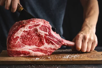 Fotobehang Butcher cuting fresh meat tomahawk steak © nerudol