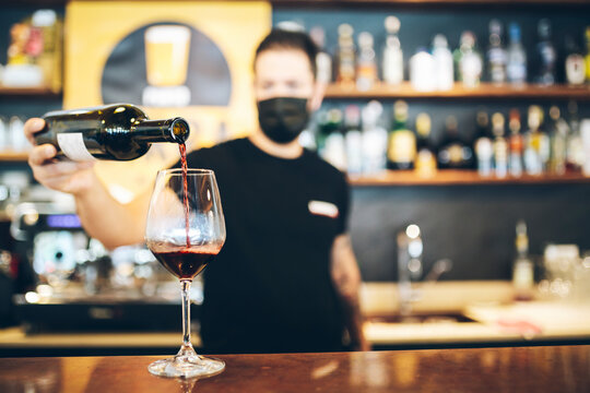 The bartender with the protective mask pours wine.covid-19, drink, restaurant