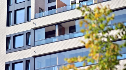 Ecological housing architecture. A modern residential building in the vicinity of trees. Ecology and green living in city, urban environment concept. Modern apartment building and green trees.
