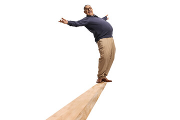 Full length shot of a funny mature man standing on a wooden beam and keeping balance