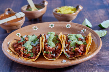 Tacos al pastor, tradicional comida mexicana, con cebolla, cilantro, piña, salsa roja o guacamole.