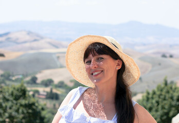 beautiful girl in a straw hat and a sundress on the background of the italian landscape 