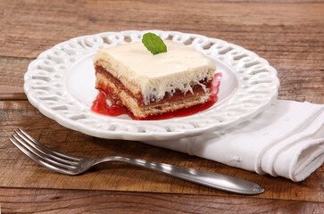 Cheesecake de morango em prato sobre tábua de madeira rústica.