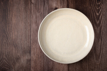 Empty plate on the wooden table. Top view of the image.