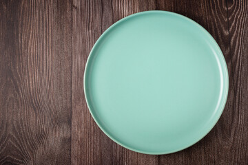 Empty plate on the wooden table. Top view of the image.