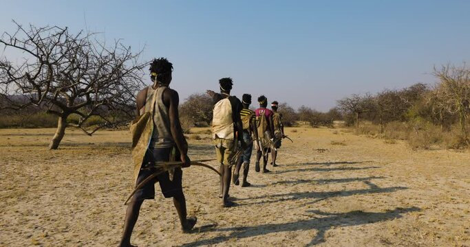 Back view of a group of Hadza hunter-gatherer tribesmen out hunding with bow and arrows Tanzania