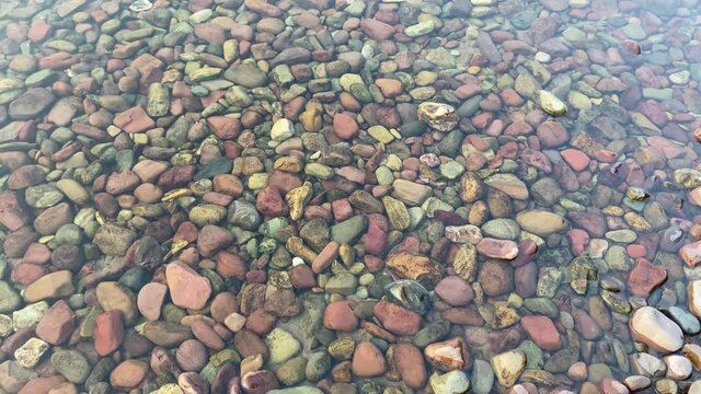 Panning shot of the colorful pebbles and rocks of Lake McDonald in Glacier National Park