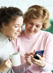 lifestyle, tehnology and people concept: mature mother and her daughter making a selfie using smart phone