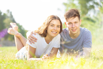 Two teenagers are lying on the grass in summertime