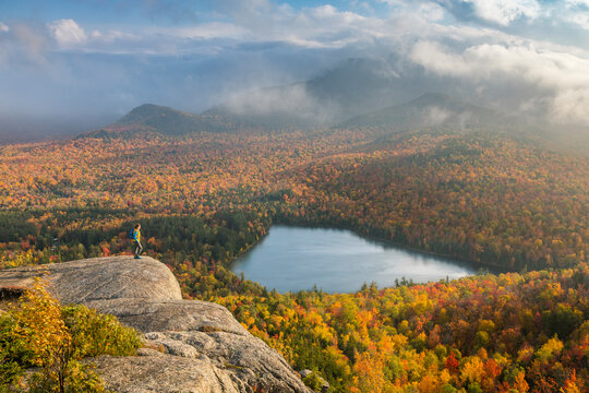 A hiker overlooking Heart Lake from near the summit of Mount Jo in New York's Adirondack Mountains.