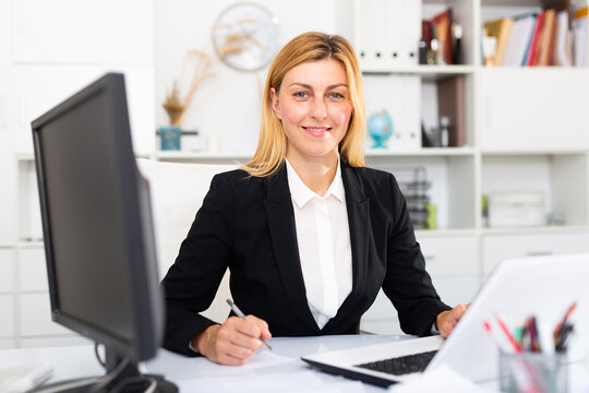 Smiling female worker engaged in business activities at workplace in office