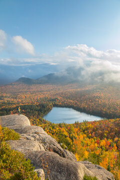 A hiker overlooking Heart Lake from near the summit of Mount Jo in New York's Adirondack Mountains.
