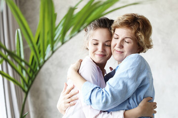 Obraz premium lifestyle and people concept - Beautiful senior mom and her adult daughter are hugging, looking at camera and smiling.