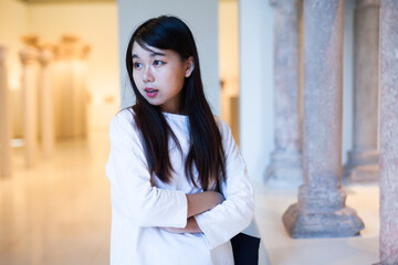 Fototapeta premium Young chinese woman visitor looking at exhibition in museum of ancient sculpture