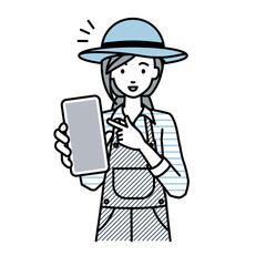 立ってスマートフォンを指差してこちらに向けて見せている農家の女性
