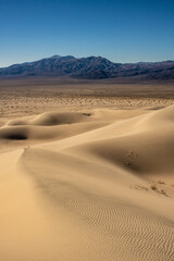 Two Hikers Climb The Panamint Dunes With The Valley And Mountains In The Distance