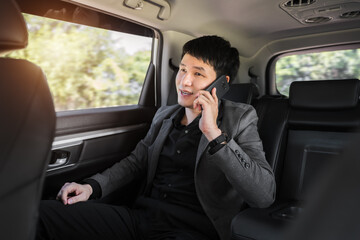 business man talking on mobile phone while sitting in the back seat of car