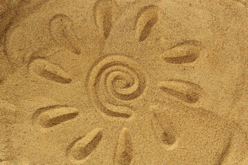 Fototapeta na wymiar The sun with rays is drawn on the sand on the beach in summer.