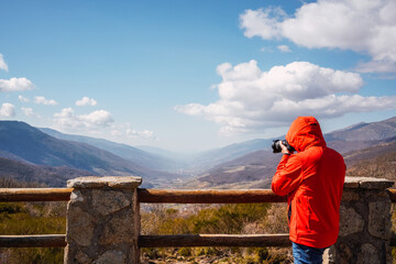 Fototapeta na wymiar unrecognizable photographer wearing red jacket taking photos of mountains. copy space.