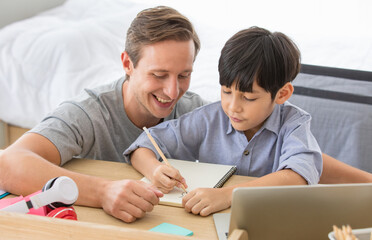 caucasian father helping his young kid with school homework using laptop during online studying together at home. Concept online learning for kid