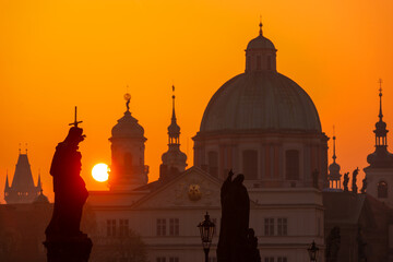 Fototapeta na wymiar Sunrise over the capital of the Czech Republic - Prague city with silhouettes of buildings and statues